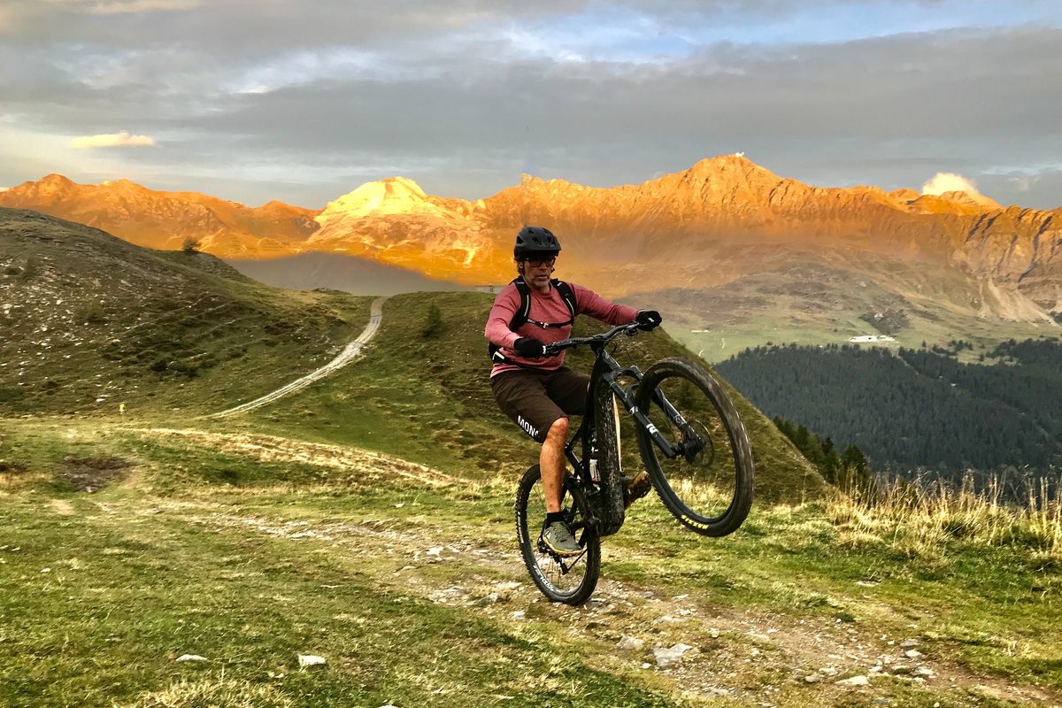 Person auf dem Mountainbike auf einem Bergweg im Abendlicht