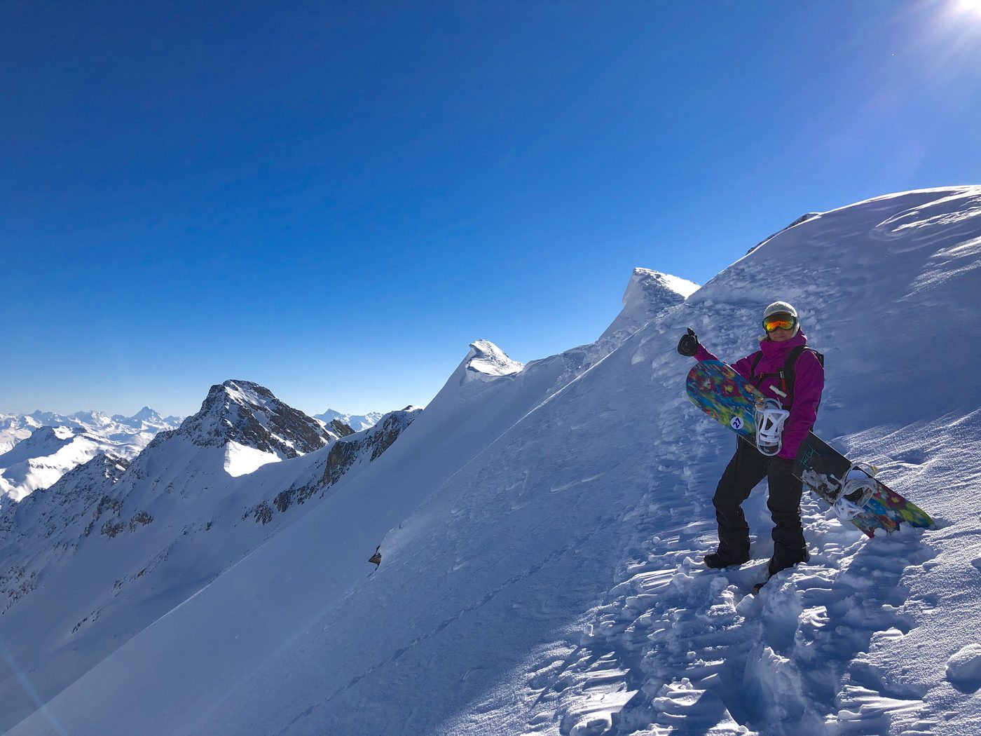 Claudia mit Snowboard auf einem verschneiten Grat