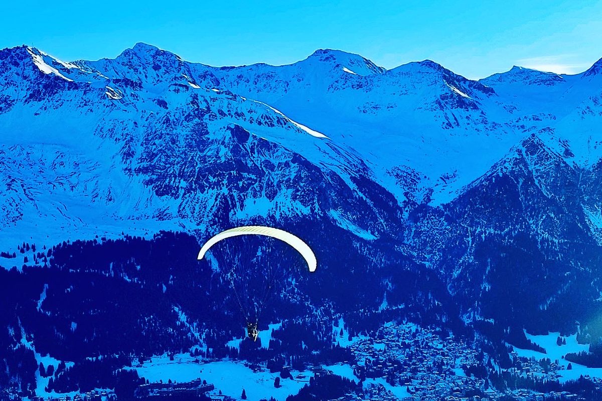 Gleitschirm über einem verschneiten Tal