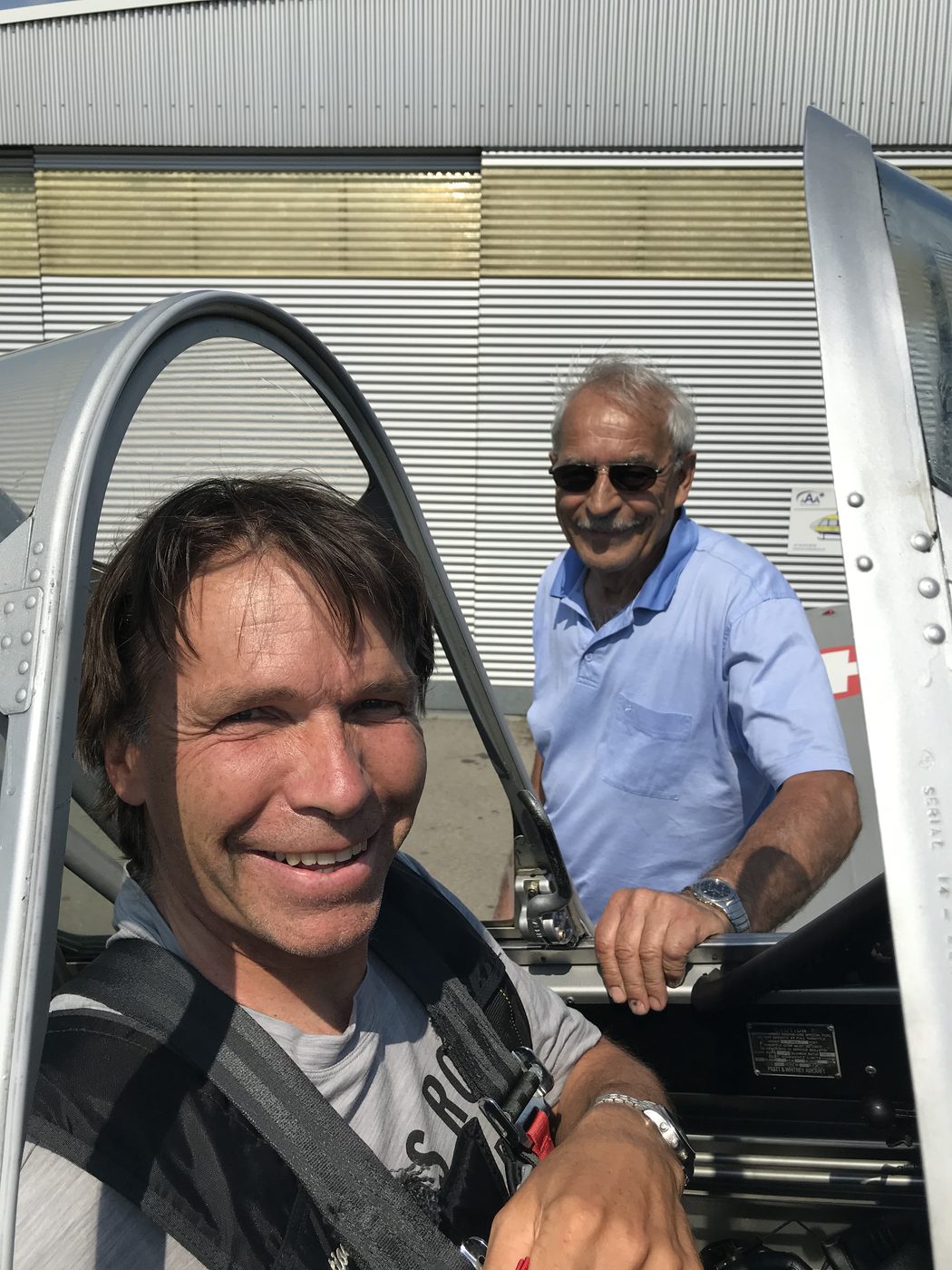 Mann im Cockpit, daneben ein zweiter Mann am Flugzeug