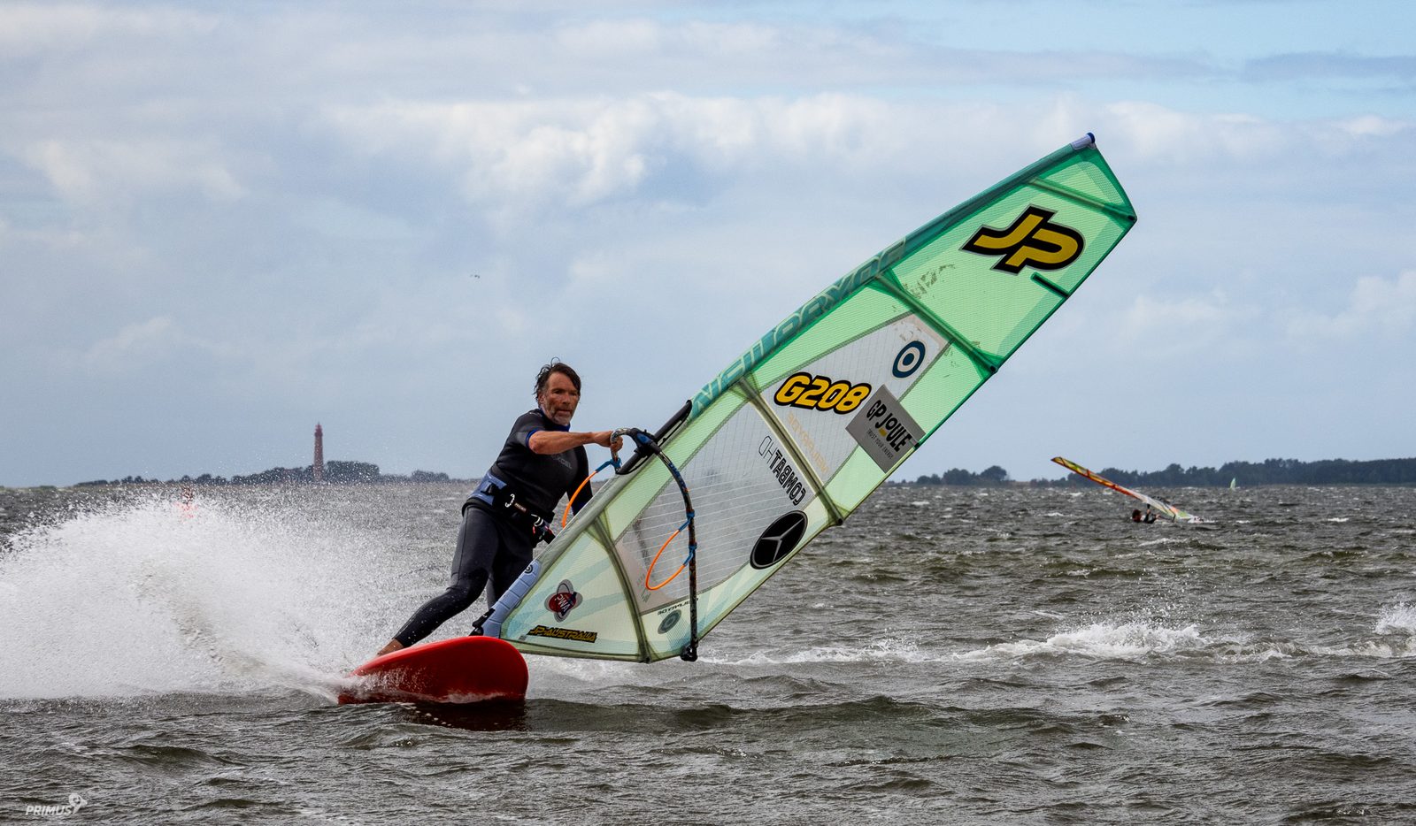 Windsurfer in voller Fahrt auf bewegtem Wasser